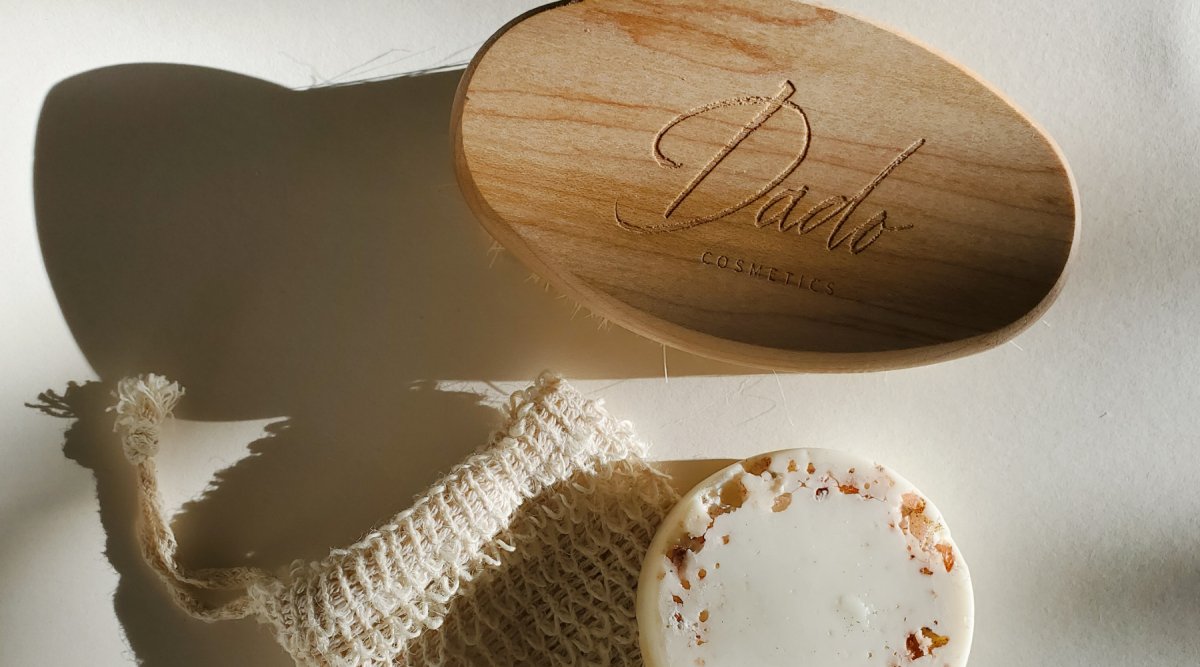 Une brosse à sec avec le logo de Dadp Cosmetics, un sac en sisal et un savon surgras au sel rose de l'Himalaya